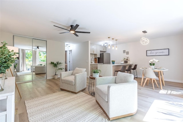 living room featuring light wood-style floors, a ceiling fan, and baseboards