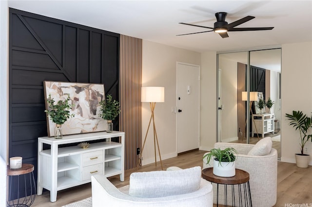 living room featuring a ceiling fan, baseboards, and light wood finished floors
