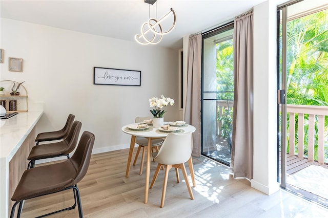 dining room featuring light wood-style floors, baseboards, and a notable chandelier