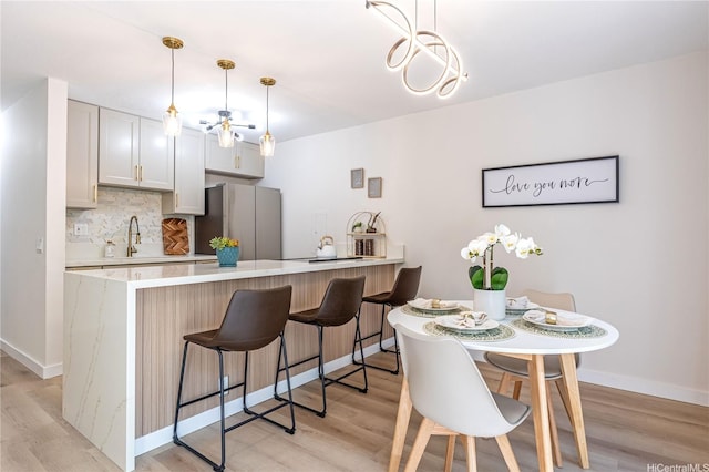 kitchen featuring light wood-type flooring, freestanding refrigerator, and backsplash