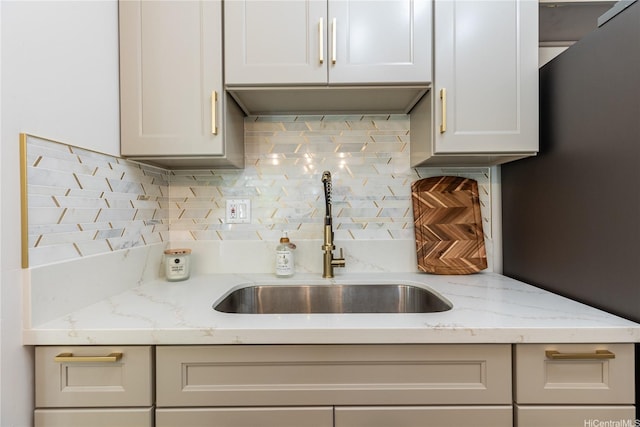 kitchen with light stone counters, a sink, and tasteful backsplash