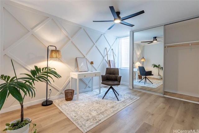 living area featuring baseboards, a ceiling fan, and wood finished floors