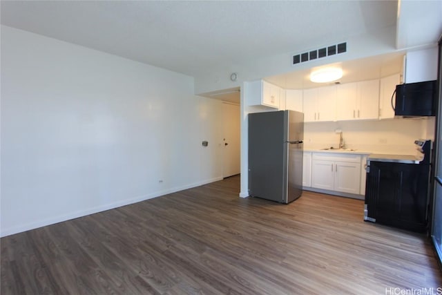 225 Queen St Unit 8C, Honolulu, HI 96813 - kitchen featuring freestanding refrigerator, black microwave, visible vents, light countertops, and dark wood-style floors