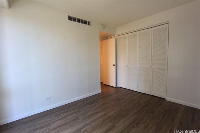 225 Queen St Unit 8C, Honolulu, HI 96813 - unfurnished bedroom with a closet, dark wood-style flooring, baseboards, and visible vents