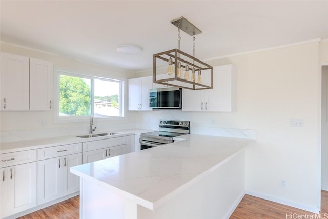 kitchen with a sink, crown molding, appliances with stainless steel finishes, and a peninsula