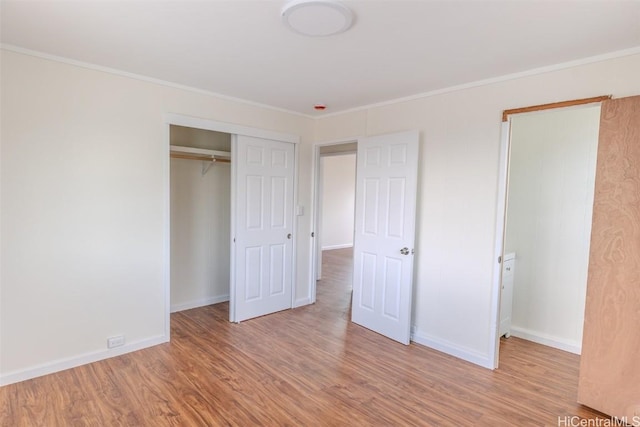 unfurnished bedroom featuring baseboards, wood finished floors, a closet, and crown molding