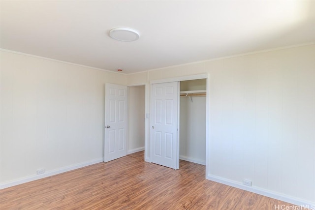 unfurnished bedroom with light wood finished floors, baseboards, a closet, and crown molding