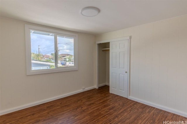 unfurnished bedroom featuring dark wood finished floors, baseboards, and a closet