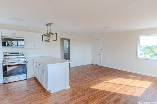 kitchen featuring light countertops, hanging light fixtures, light wood finished floors, a peninsula, and appliances with stainless steel finishes