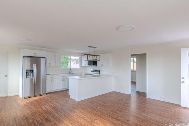 kitchen with light countertops, wood finished floors, appliances with stainless steel finishes, and a peninsula