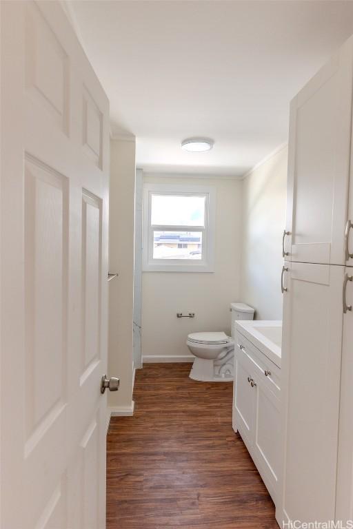 bathroom with baseboards, wood finished floors, toilet, and vanity