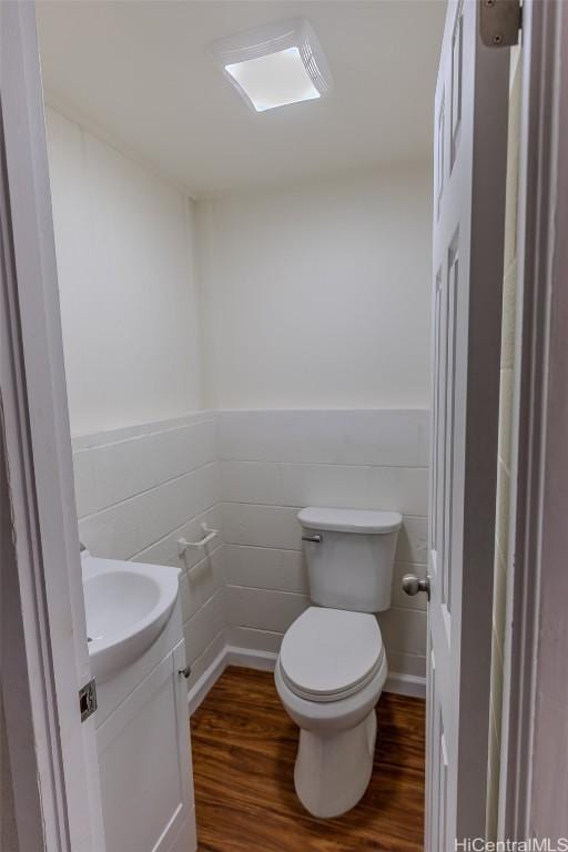 bathroom featuring wood finished floors, vanity, toilet, and wainscoting