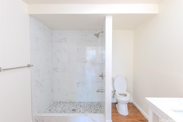 bathroom featuring walk in shower, baseboards, toilet, wood finished floors, and vanity