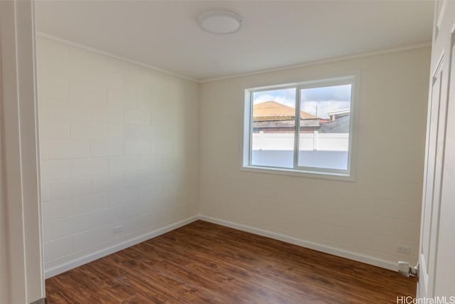 spare room featuring crown molding, baseboards, and dark wood finished floors