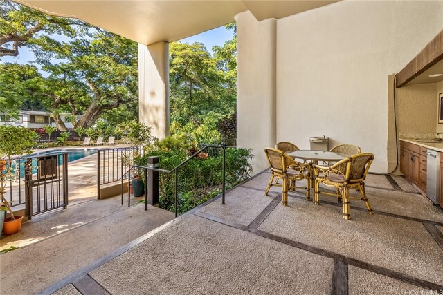 view of patio featuring outdoor dining space, an outdoor pool, a balcony, and a sink