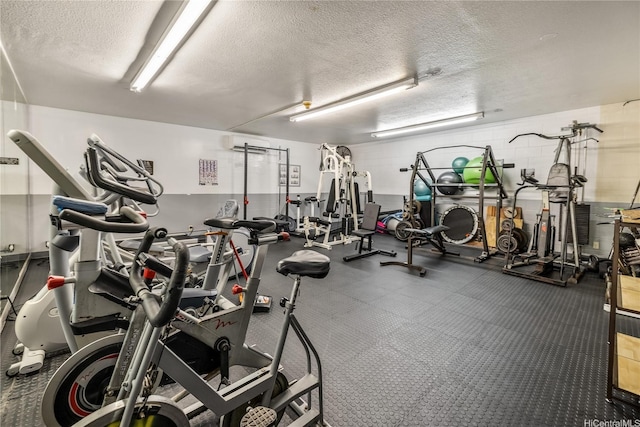 exercise room featuring a wall mounted AC and a textured ceiling