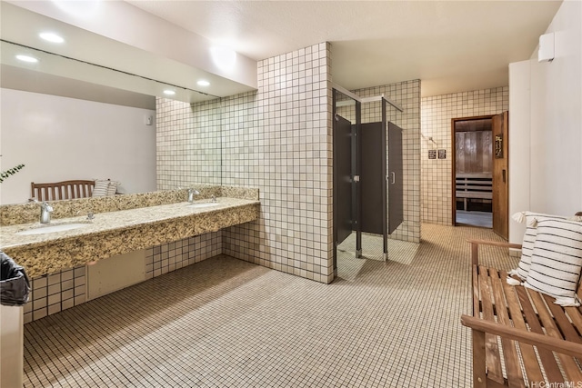 full bathroom with a stall shower, tile patterned floors, a sink, and tile walls