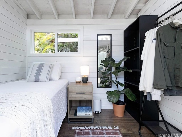 bedroom featuring wood walls, beam ceiling, and wood finished floors