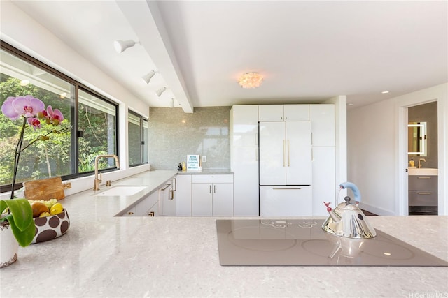 kitchen featuring light countertops, white refrigerator, white cabinets, electric stovetop, and a sink