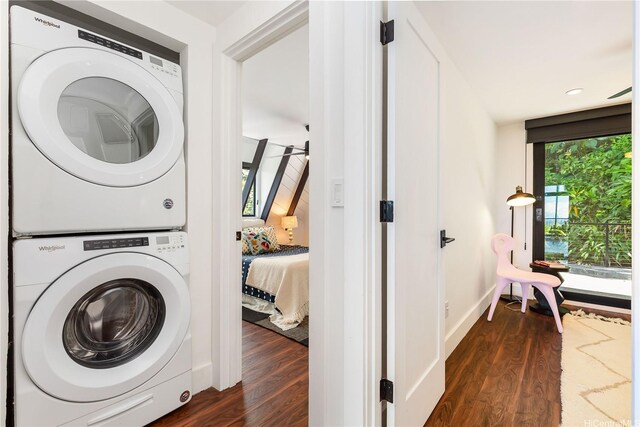 washroom with dark wood-style floors, stacked washer / drying machine, laundry area, and baseboards