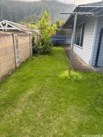 view of yard with a trampoline, a fenced backyard, and a mountain view