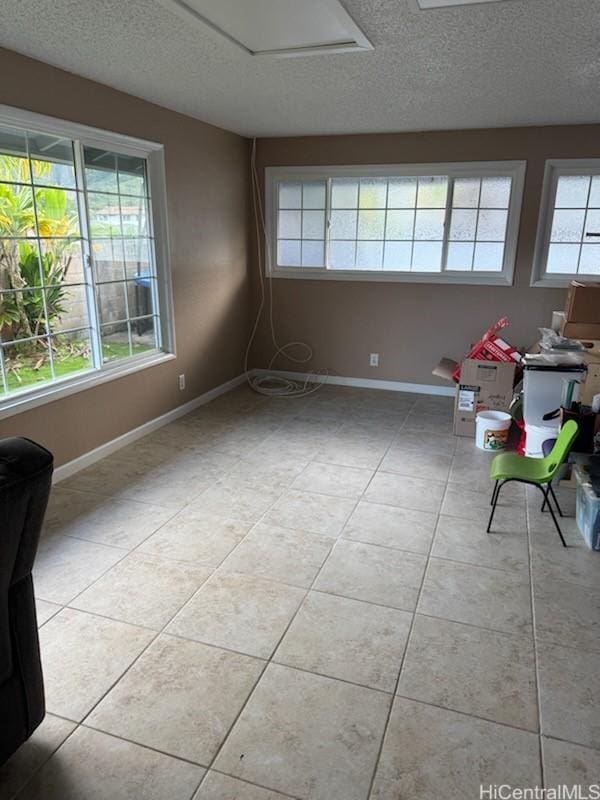 empty room with a textured ceiling, baseboards, and light tile patterned floors