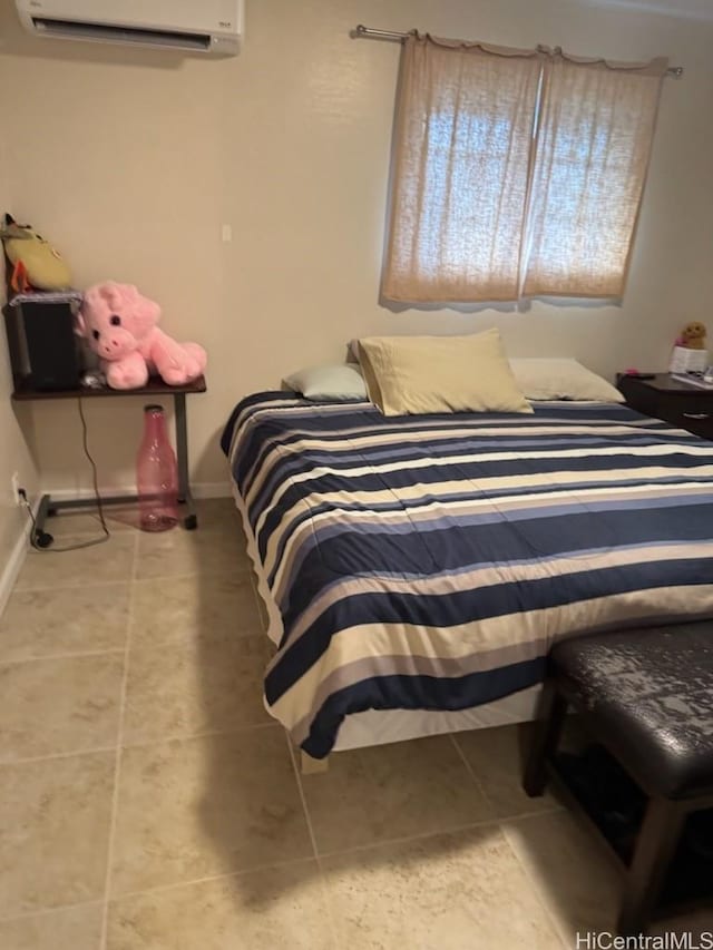 bedroom featuring tile patterned floors, baseboards, and a wall unit AC