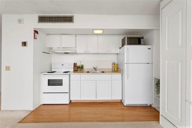 kitchen with a sink, white appliances, white cabinetry, under cabinet range hood, and visible vents
