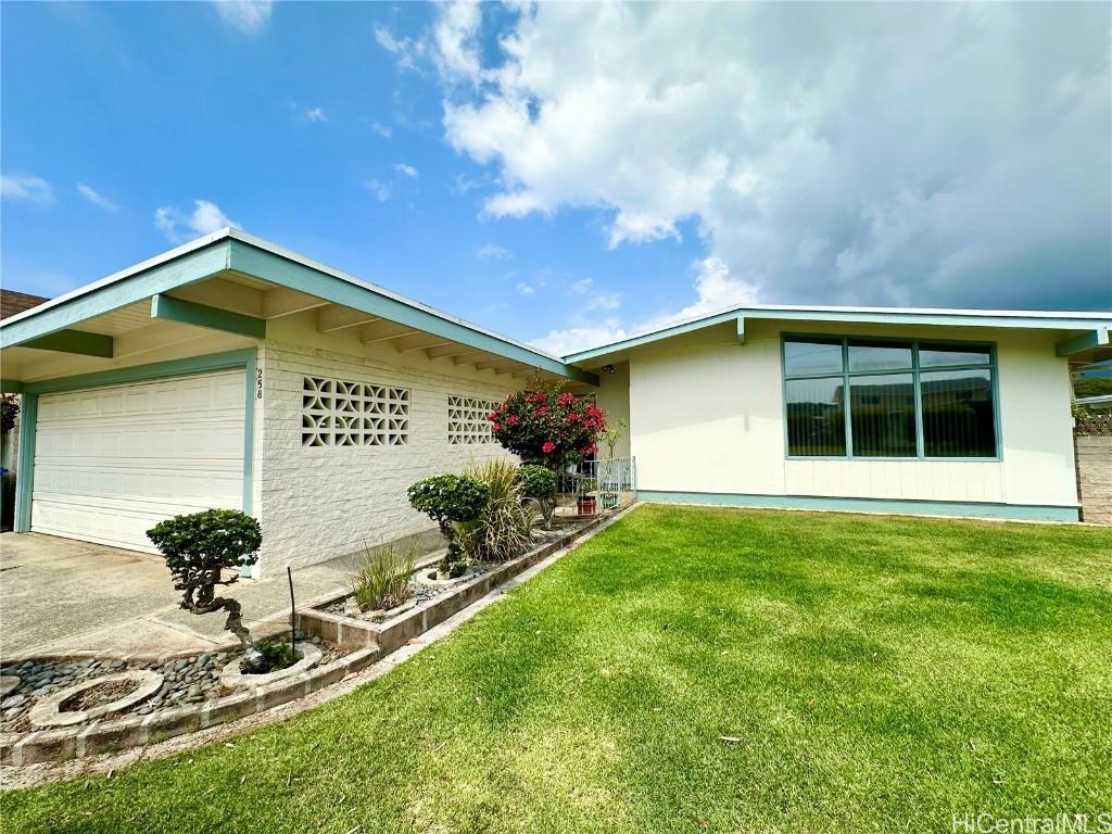 view of front of property featuring driveway, a front yard, and a garden
