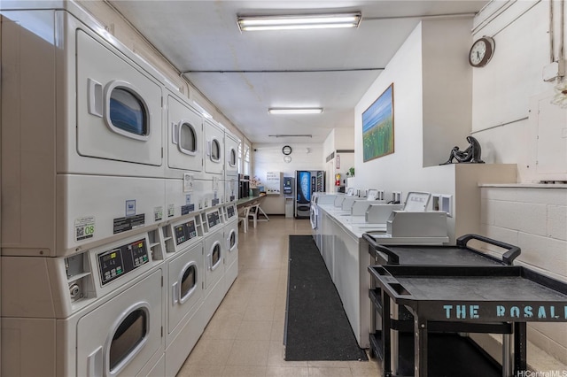 community laundry room featuring light tile patterned floors, stacked washing maching and dryer, and washer and clothes dryer