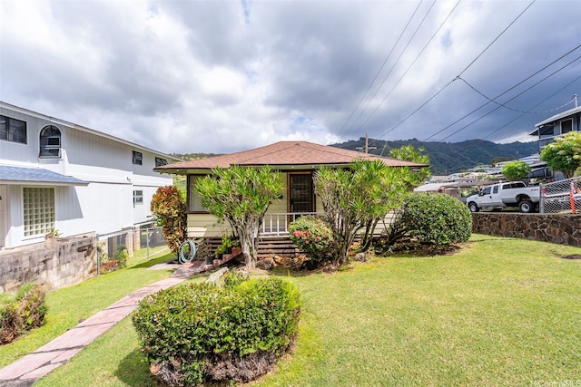 view of front of property with a mountain view, fence, and a front yard