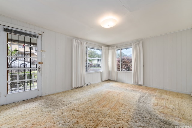 carpeted empty room featuring wooden walls