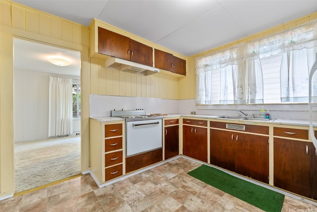 kitchen featuring electric range, wood walls, a sink, light countertops, and under cabinet range hood