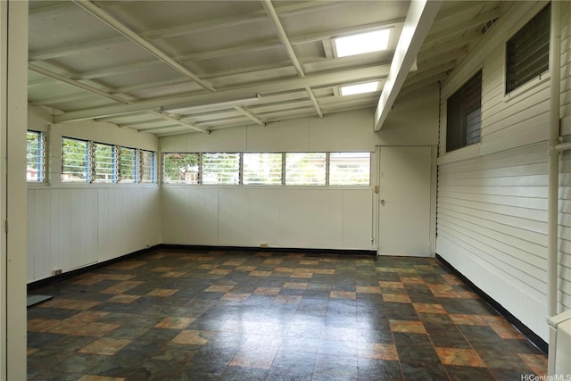 empty room featuring wood walls and lofted ceiling