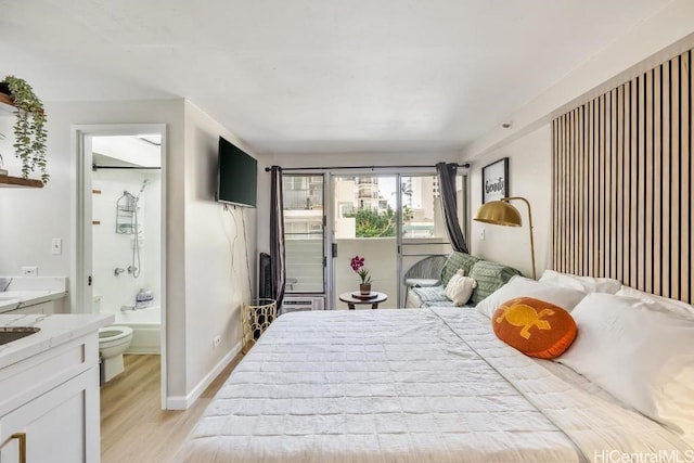 bedroom featuring baseboards, ensuite bathroom, and light wood finished floors
