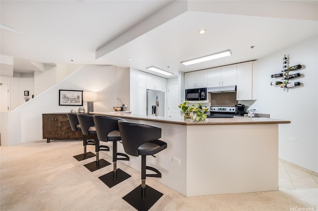 725 Kapiolani Blvd Unit 3503, Honolulu, HI 96813 - kitchen featuring white cabinets, light colored carpet, appliances with stainless steel finishes, a breakfast bar area, and under cabinet range hood