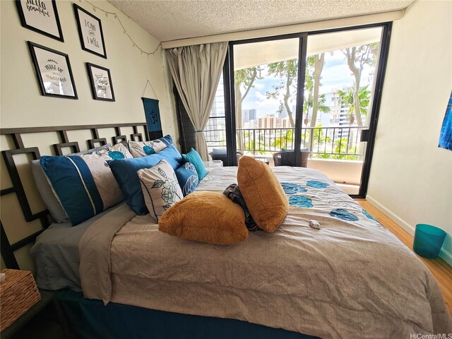 bedroom with wood finished floors, a textured ceiling, baseboards, multiple windows, and access to exterior
