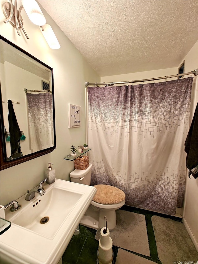 full bath featuring a textured ceiling, a sink, toilet, and a shower with curtain