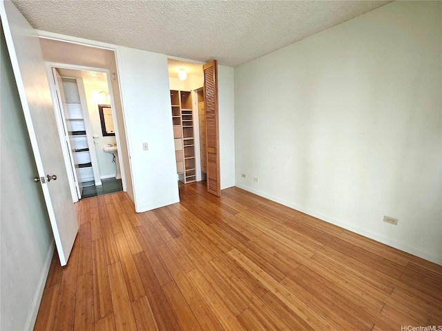 965 Prospect St Unit 307, Honolulu, HI 96822 - unfurnished bedroom with light wood finished floors, a closet, baseboards, a textured ceiling, and a spacious closet