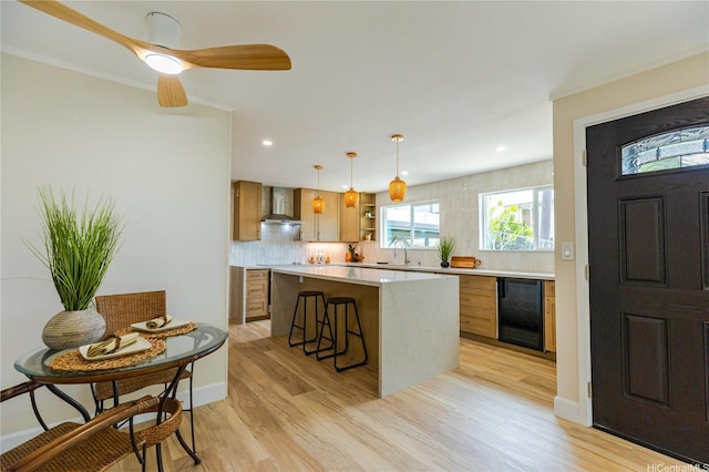 kitchen featuring wall chimney exhaust hood, open shelves, light countertops, a sink, and wine cooler