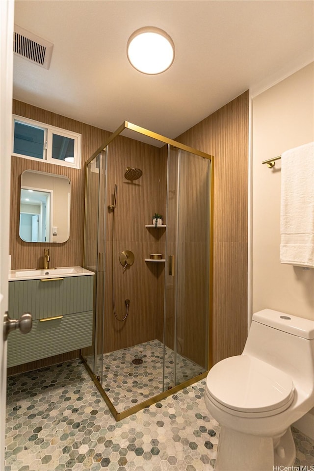 bathroom featuring toilet, a stall shower, and visible vents