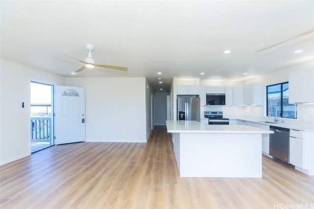 kitchen with light wood-style flooring, a center island, light countertops, and appliances with stainless steel finishes