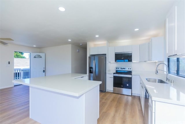 kitchen with light countertops, a center island, light wood-style floors, stainless steel appliances, and a sink