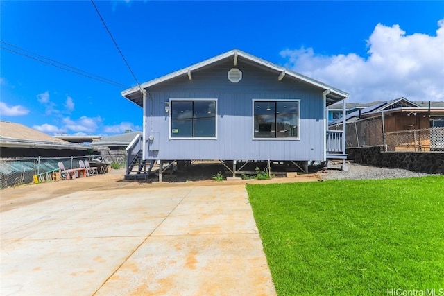 back of house featuring fence, a lawn, and concrete driveway