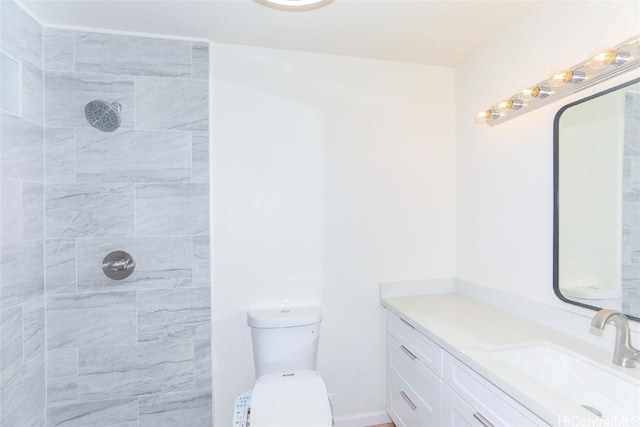 bathroom featuring a tile shower, vanity, and toilet
