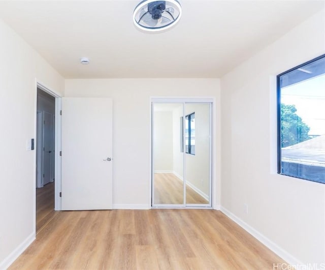 unfurnished bedroom with a closet, baseboards, and light wood finished floors