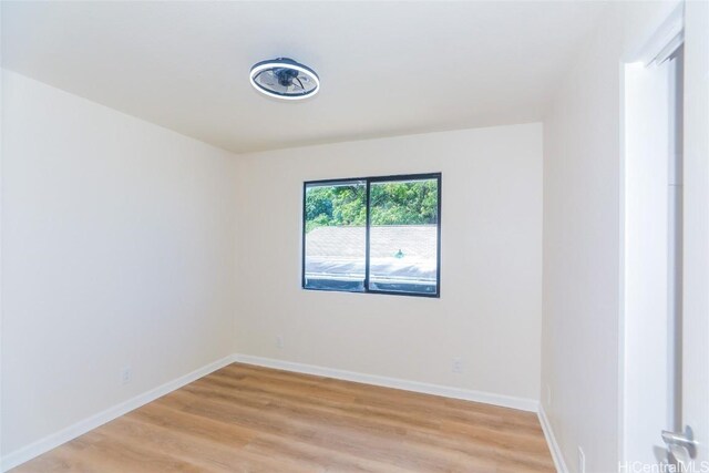 spare room with baseboards and light wood-type flooring