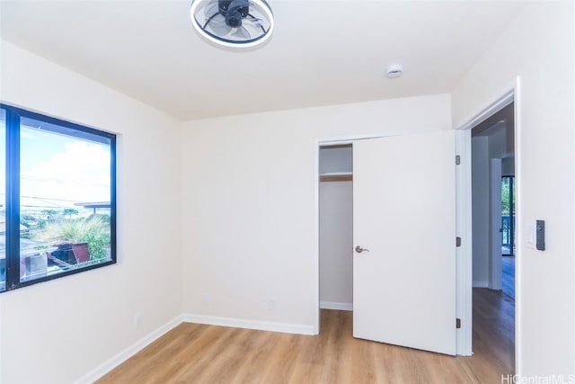 unfurnished bedroom featuring a closet, baseboards, and light wood-type flooring