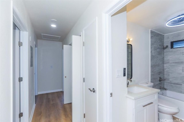 hall with a sink, visible vents, baseboards, and wood finished floors