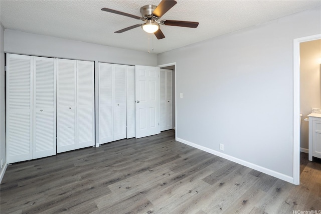 94-313 Ulukoa St, Mililani, HI 96789 - unfurnished bedroom with two closets, wood finished floors, baseboards, a textured ceiling, and a ceiling fan